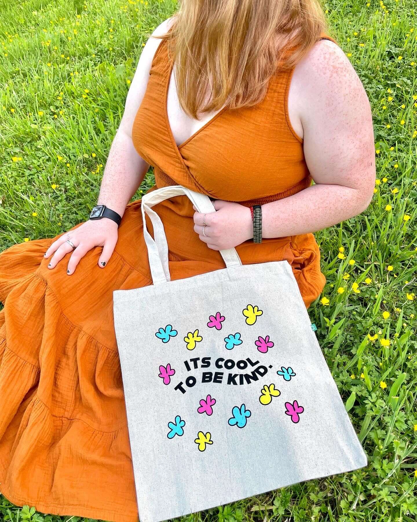 Girl sitting with Kindness is Cool tote in flowers