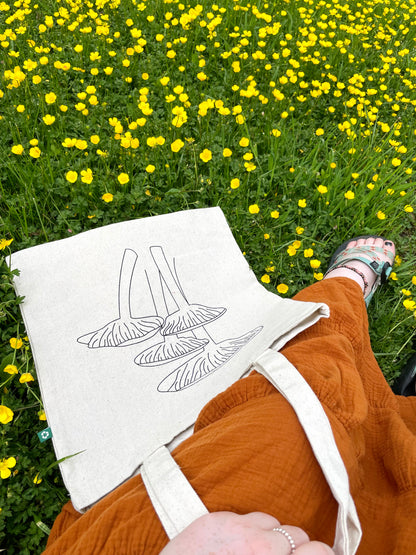 Girl sitting in flowers with Keep it Shroomy tote in lap