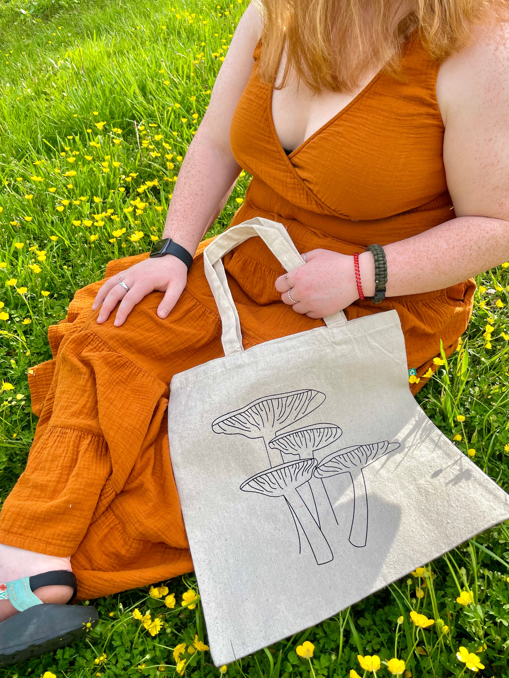 Girl sitting with Keep it Shroomy tote in flowers