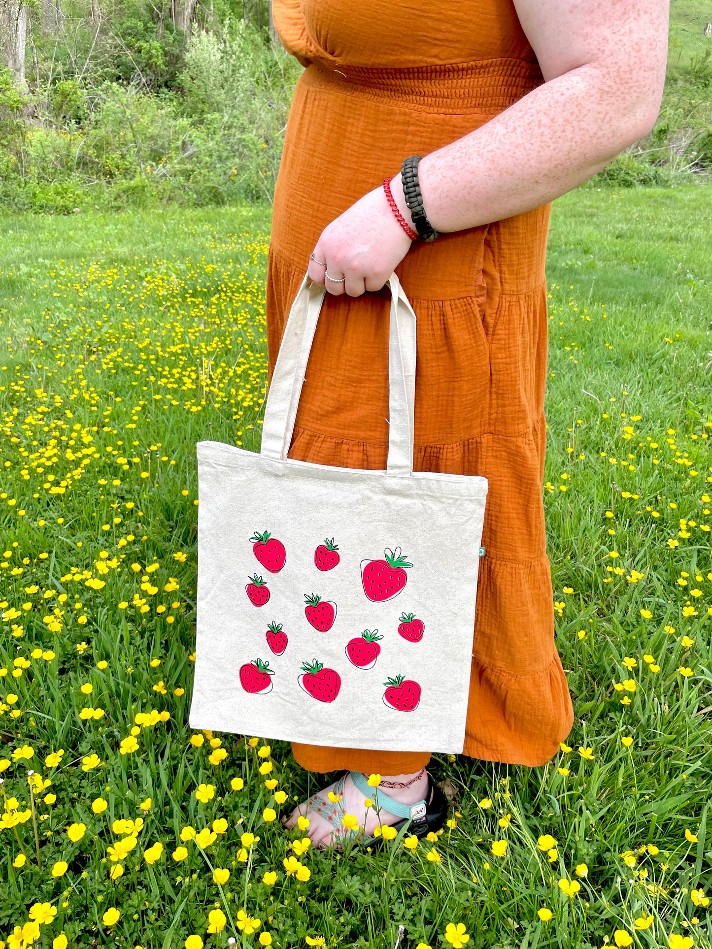 Girl holding Super Berry tote at angle in flowers