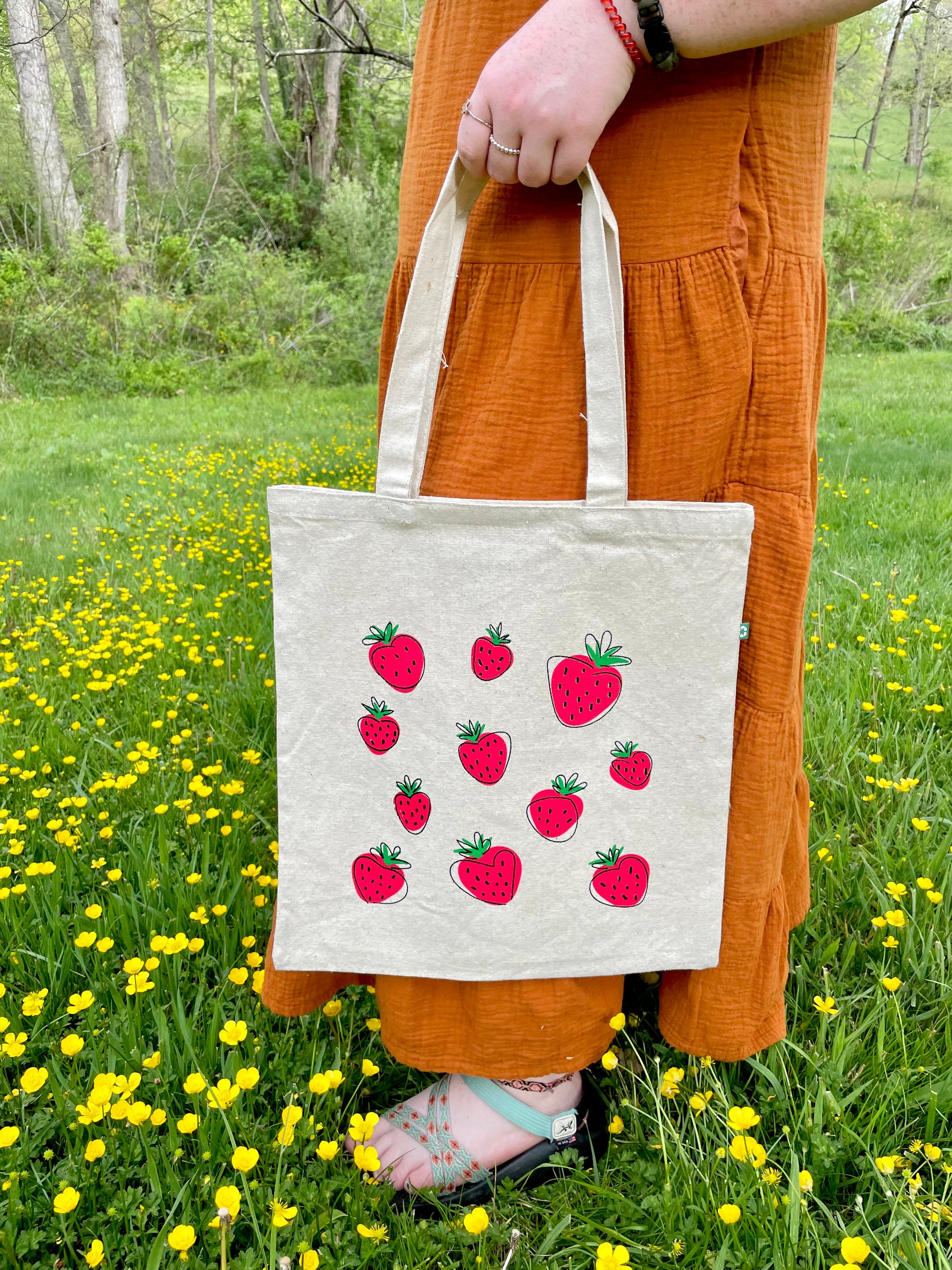 Girl holding Spaced Out tote by her side in flowers