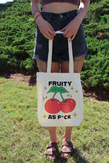 Girl holding Fruity AF tote with two hands in front of body