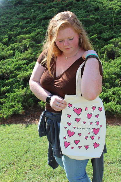 Girl looking down at Lots of Love tote over shoulder