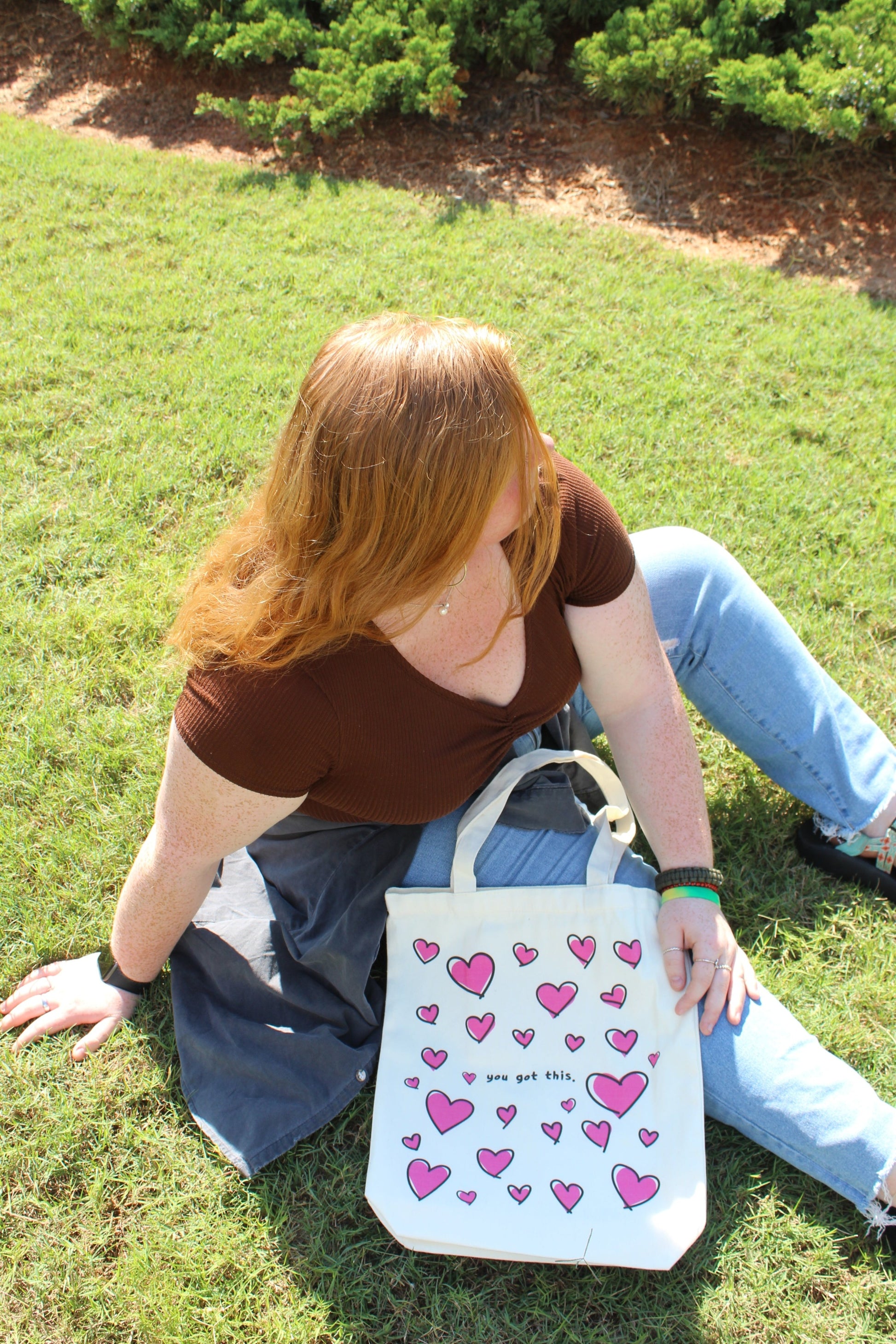 Girl sitting outside forward away with Lots of Love tote