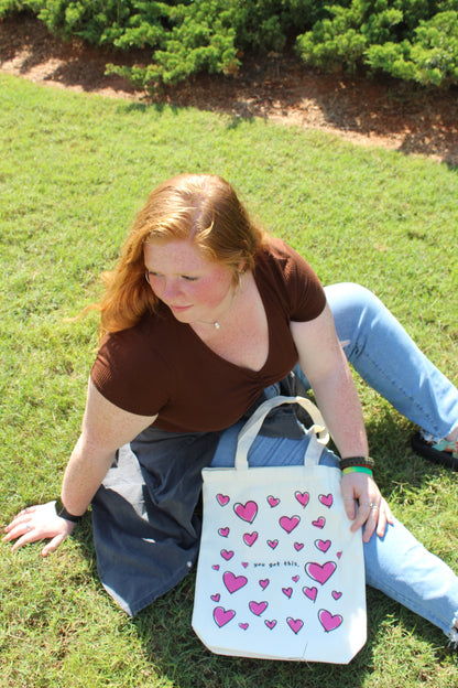 Girl sitting outside looking back with Lots of Love tote