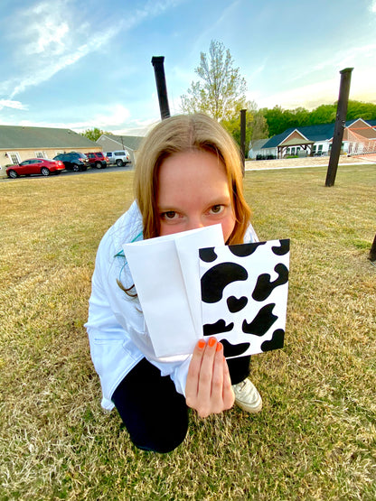 Girl holding Cow print postcard outside