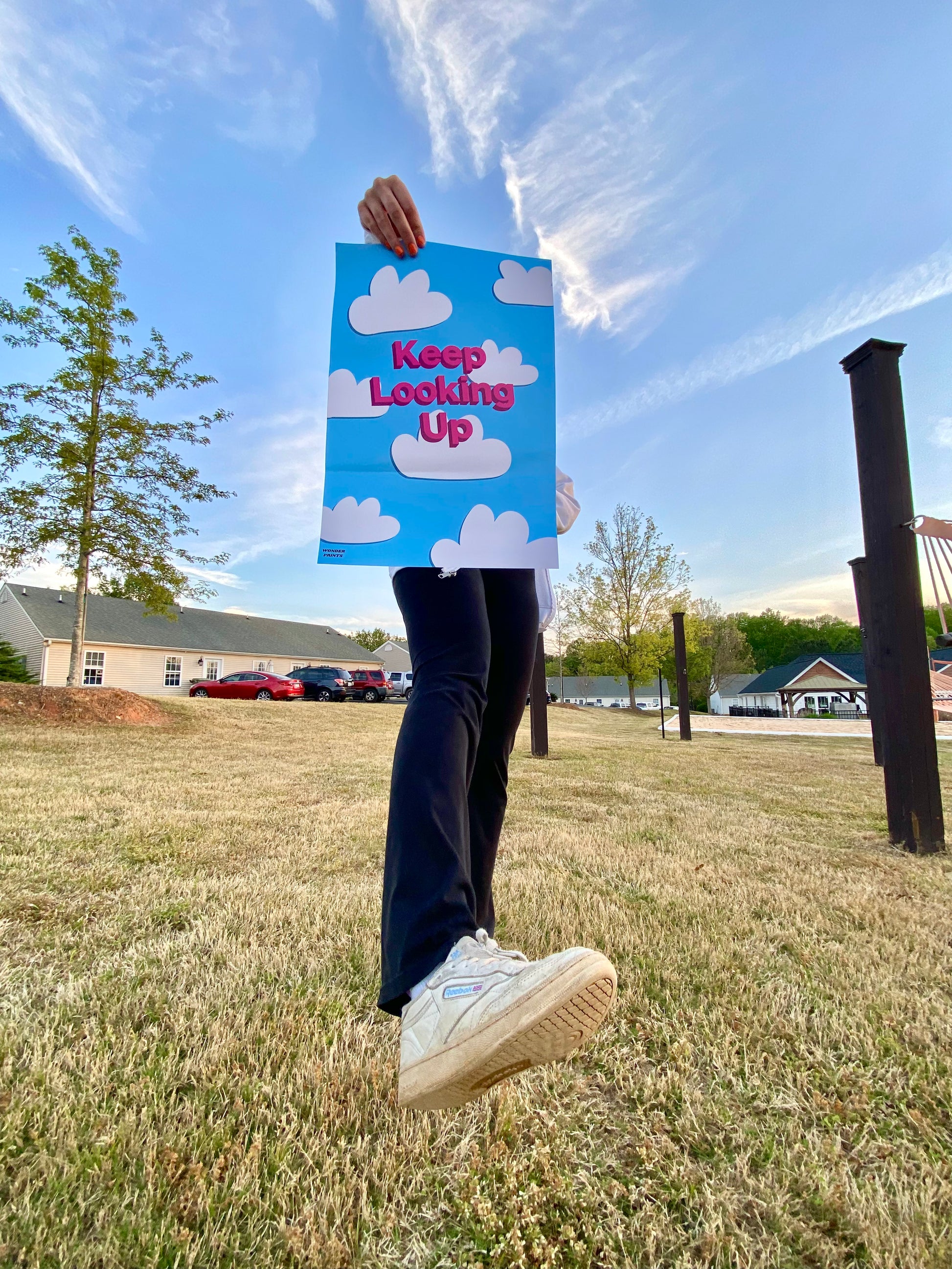 Girl showing off a cloudy design encouragement poster outside