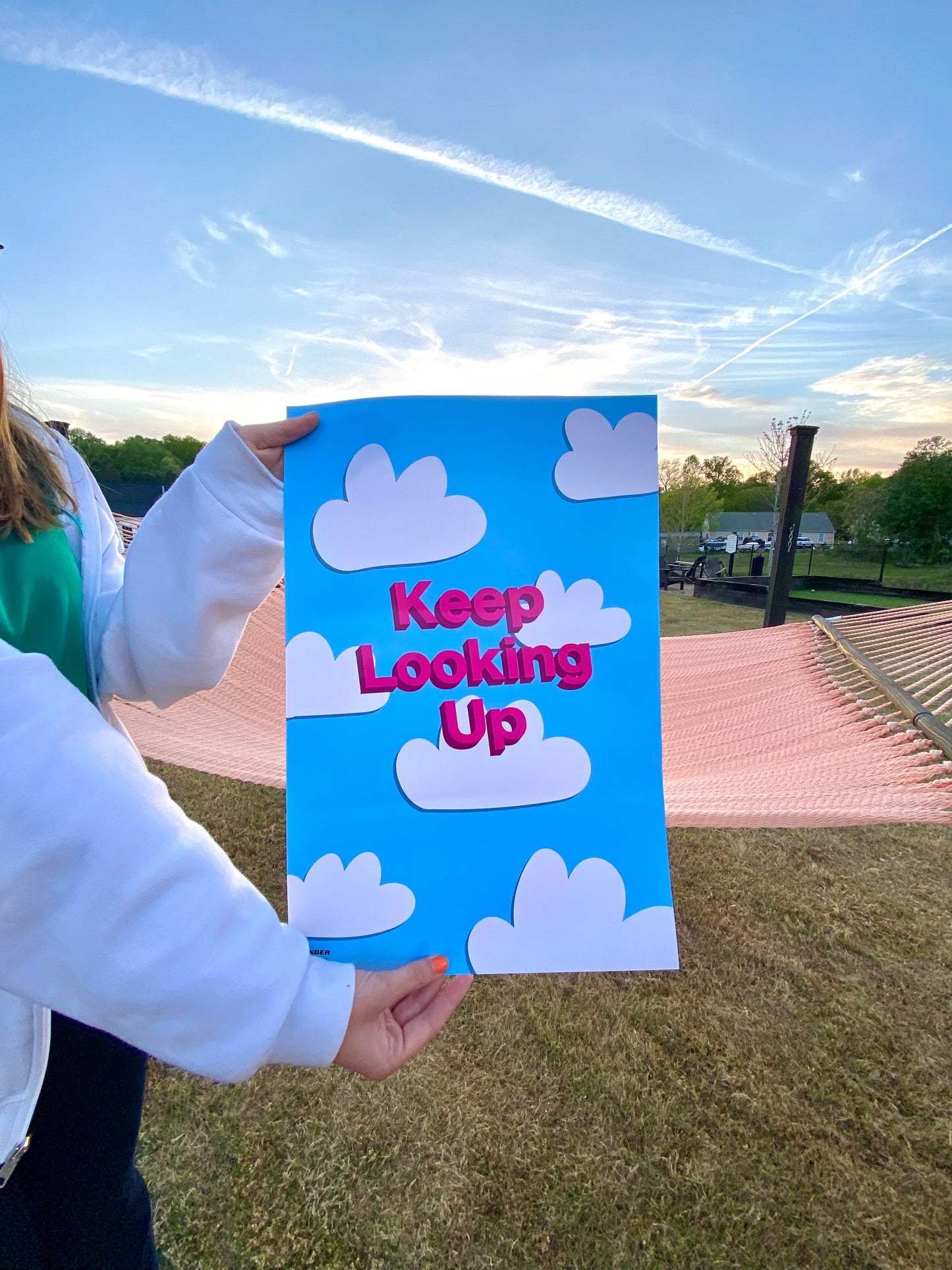 Girl holding up the Cloudy Design encouragement poster from the side