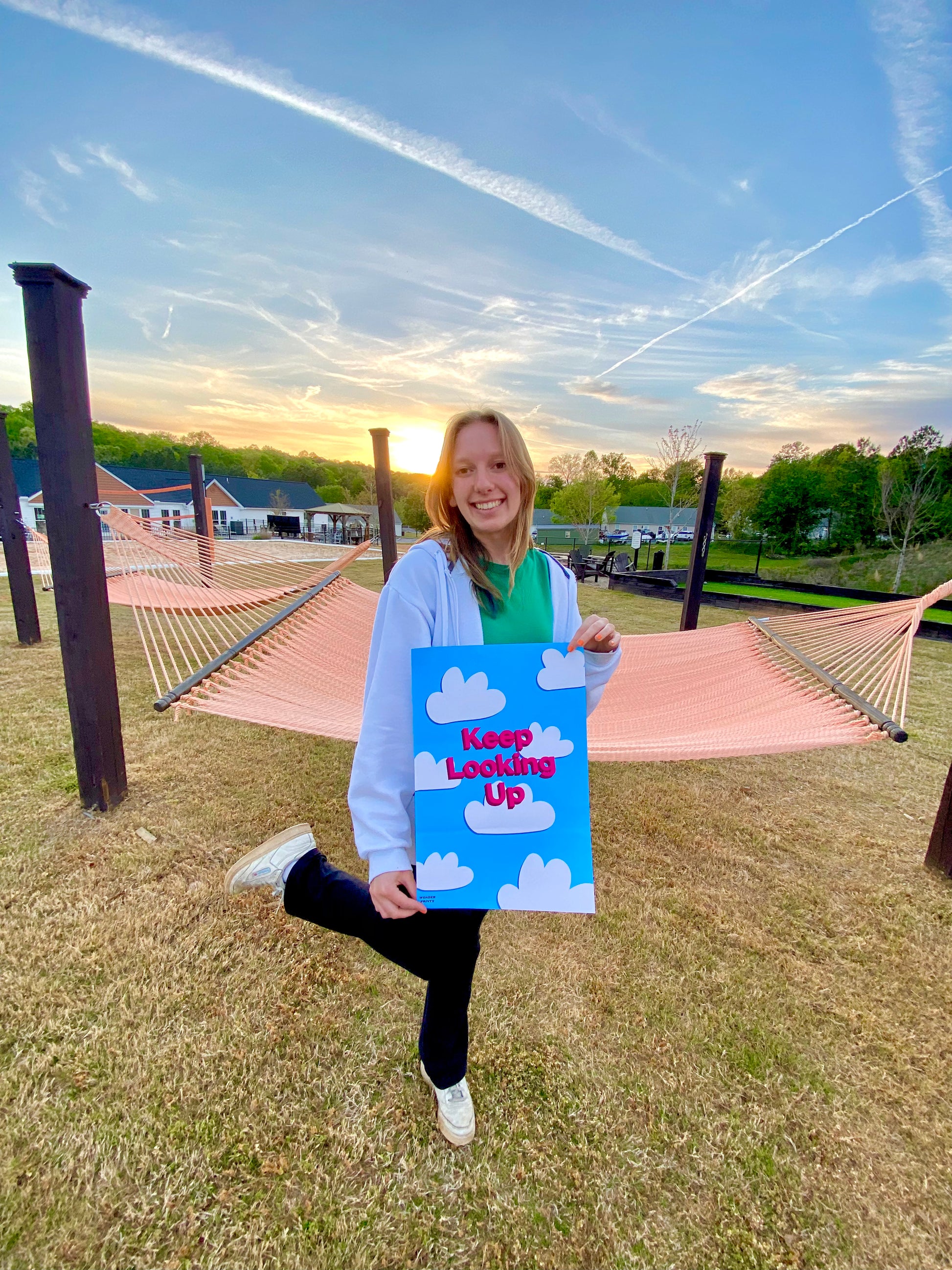 Girl holding up Cloudy Encouragement Poster in sunset