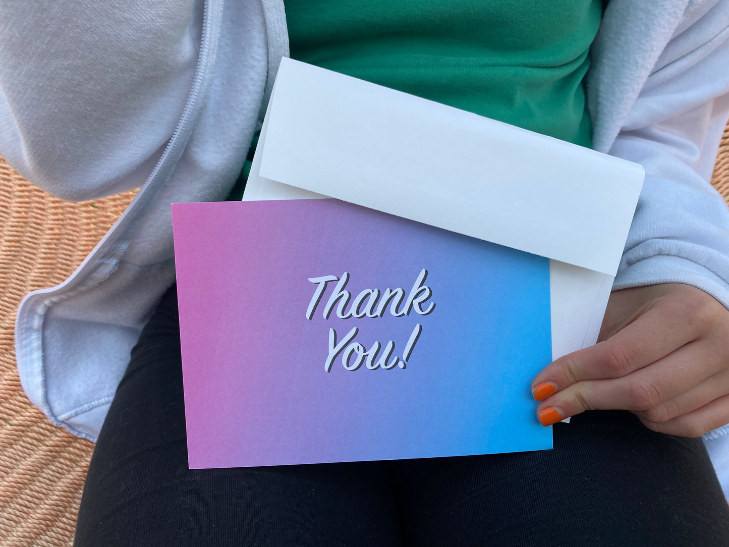 Girl holding blue and pink thank you card with envelope