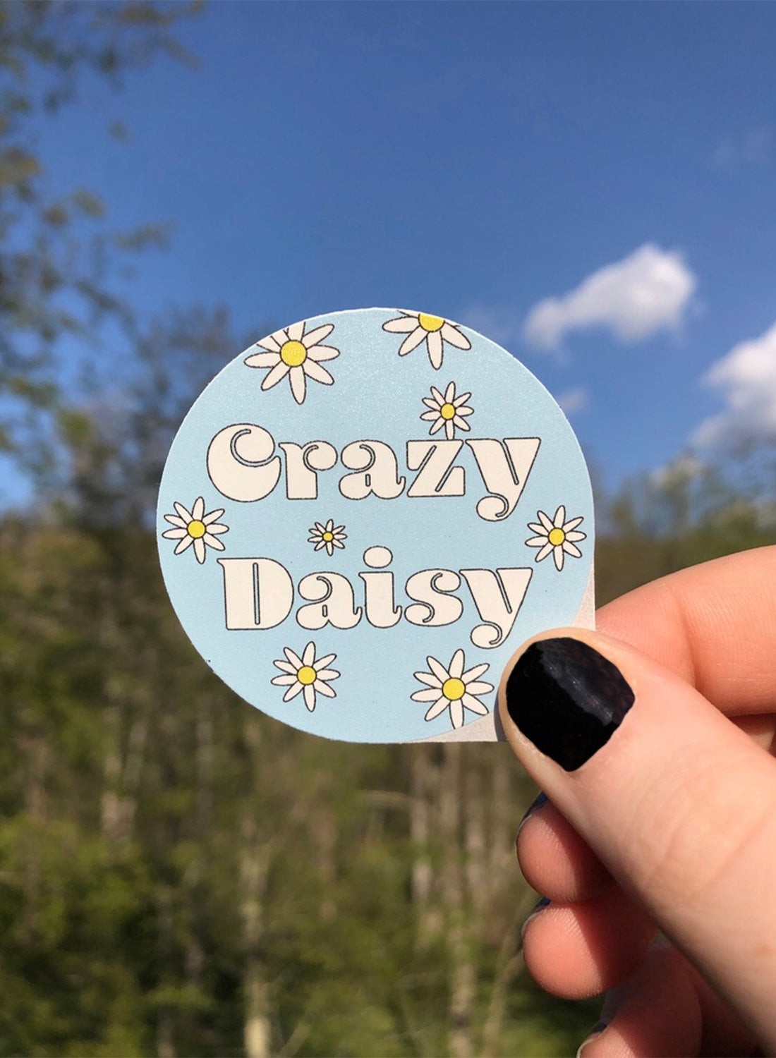 Girl holding Crazy Daisy sticker outside close up