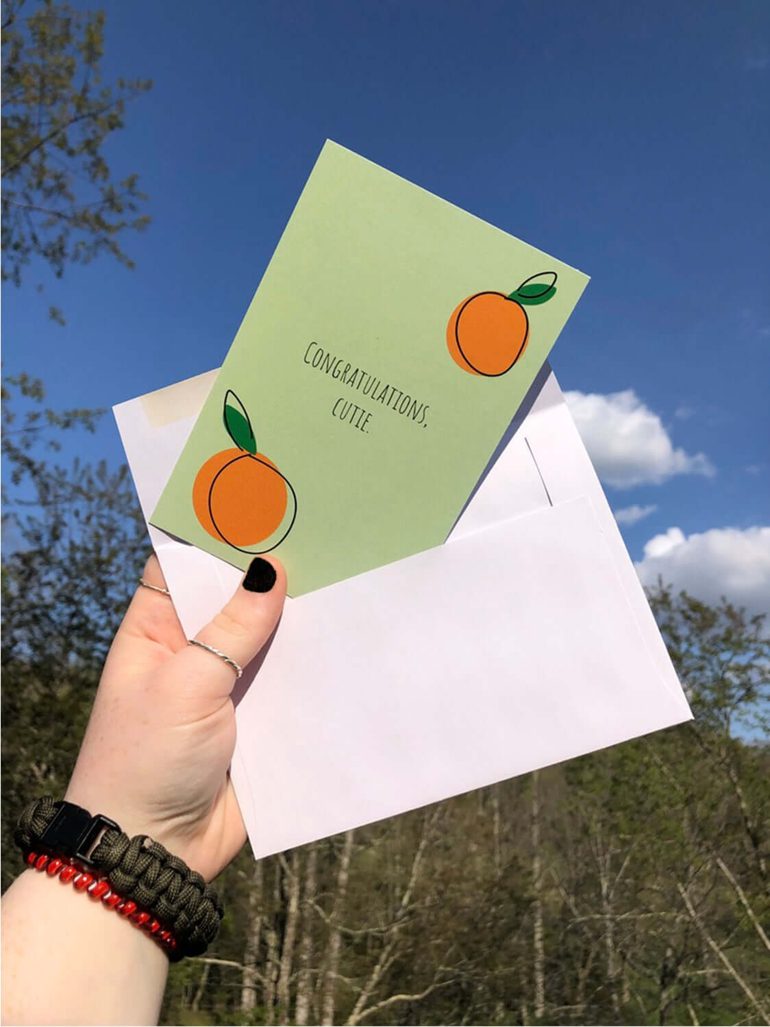 Girl holding Congratulations Cutie postcard in envelope outside